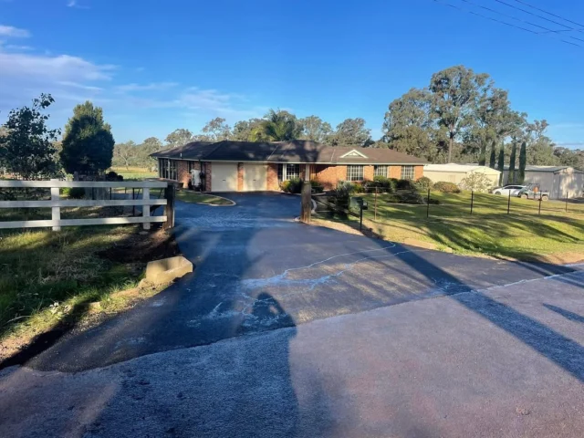 The driveway completed in the winter of 24. Over 2 days the crew removed the old road base and installed a drainage system in front of the garage to prevent water intrusion. New road base was then placed, compacted, and the surface was finished with fresh asphalt.